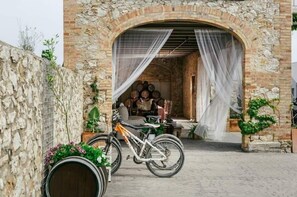 A stone building with a rustic archway, a bicycle, and barrels. - Cortijo Cal Rajoler (Cabanes)