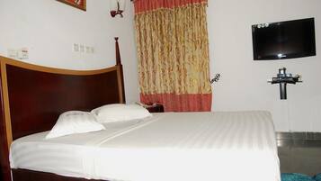 A hotel room with a wooden bed, a television mounted on the wall, and a curtain with a floral pattern.