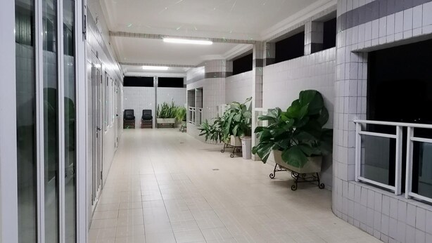 A clean, well-lit hallway with tiled floors, large windows, and potted plants. - Hotel Paramondo (Abomey-Calavi)