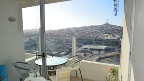 A balcony with a glass door, a round table, and two chairs. - Lunoma Departamento (Coquimbo)