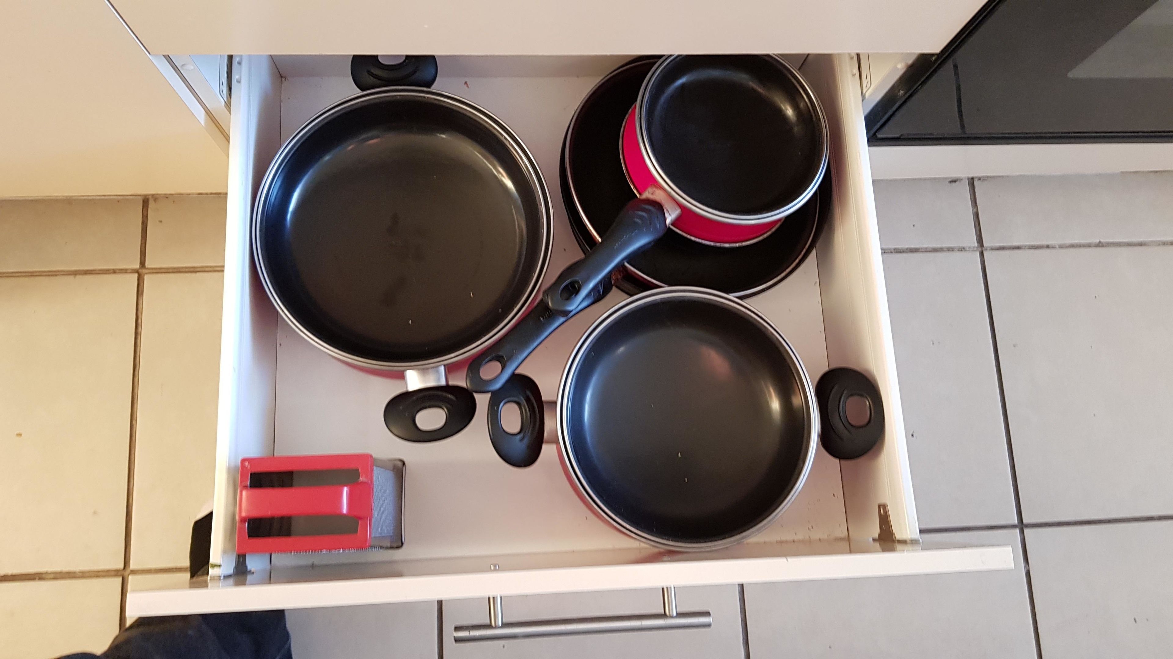 Een keuken met drie koekenpannen op een fornuis.