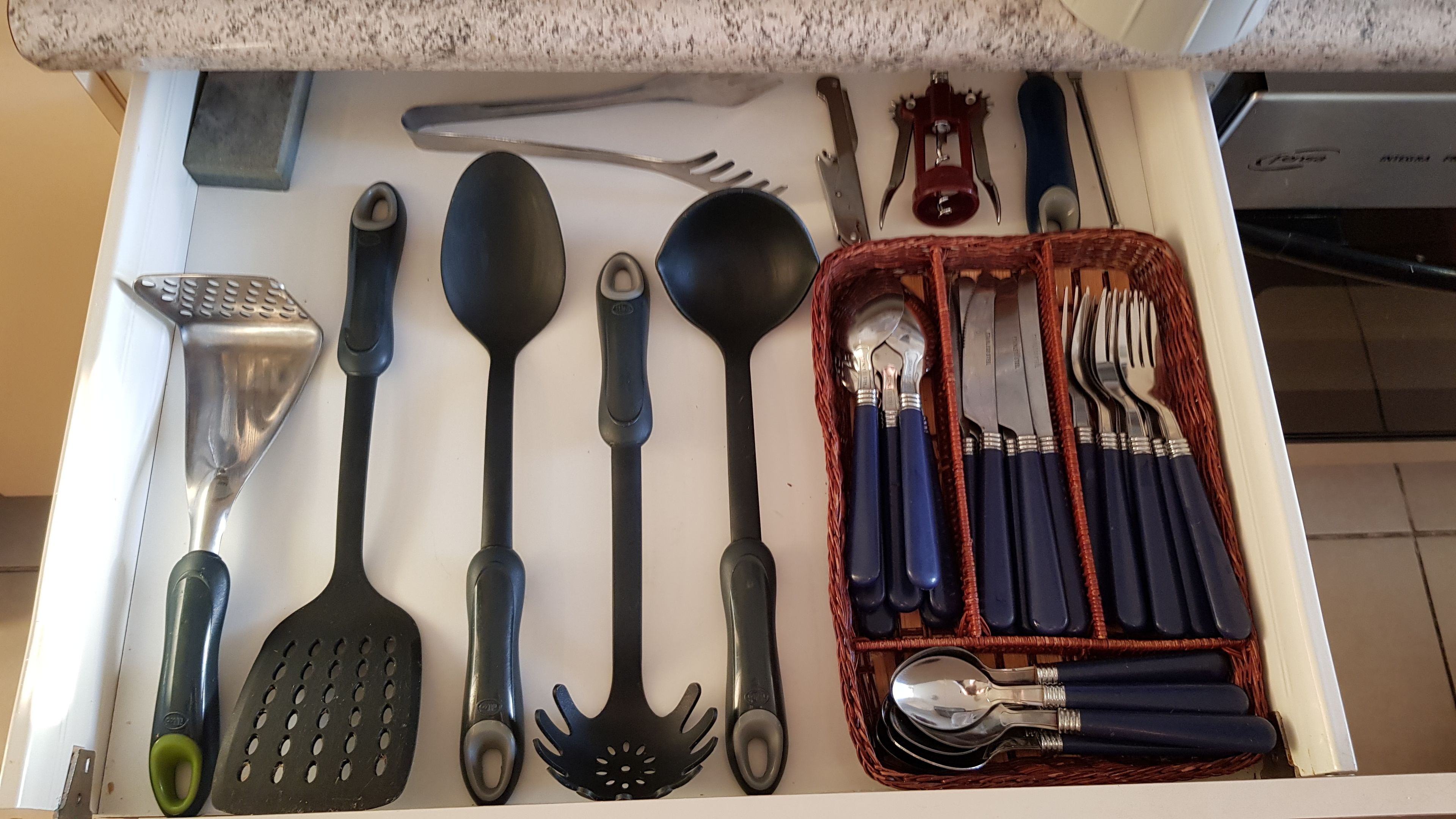 Un tiroir contenant divers ustensiles de cuisine, notamment des cuillères, des spatules et un ensemble de couteaux.