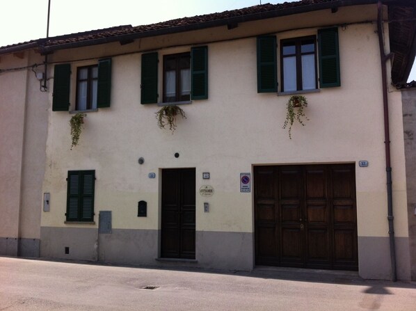A building with a beige facade, green shutters, and a large wooden door. - Ai Cappuccini (Racconigi)