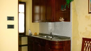 A kitchen with wooden cabinets, a granite countertop, and a sink. - Ai Cappuccini (Racconigi)