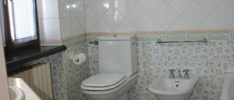 Une salle de bain équipée de toilettes, d’un bidet et d’un lavabo.