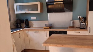 Une cuisine moderne avec des meubles en bois, un four encastré et un grand îlot central doté d’un tabouret.