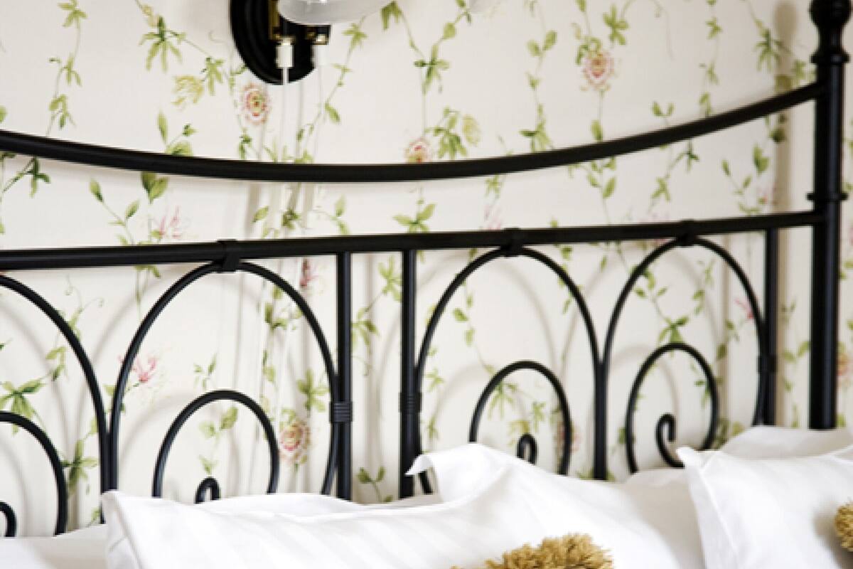 A bed with white linens and a single decorative pillow.