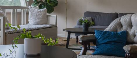 A cozy living room with a sofa, armchair, and a round table with a plant.