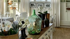 A dining area with a table set for two, a large green vase, and a hanging light fixture. - Korstäppans Herrgård (Leksand)