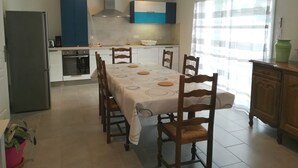 A modern kitchen with a dining area, featuring a large table, chairs, and a refrigerator. - New detached house 2 km from Ondres beach, ideal for 6, 8 people (Ondres)