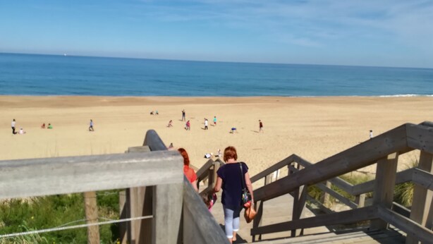 A wooden staircase leading to a beach with people walking on the sand. - New detached house 2 km from Ondres beach, ideal for 6, 8 people (Ondres)