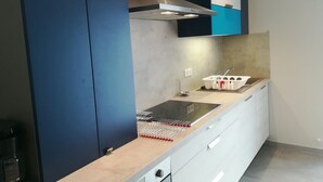A modern kitchen with a built-in stove, a range hood, and a sink. - New detached house 2 km from Ondres beach, ideal for 6, 8 people (Ondres)