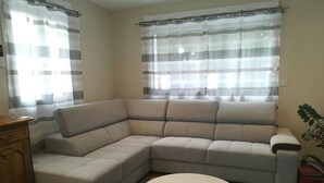 A living room with a beige sectional sofa, a round glass coffee table, and a wooden cabinet. - New detached house 2 km from Ondres beach, ideal for 6, 8 people (Ondres)