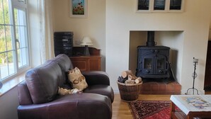 Una sala de estar acogedora con un sofá de cuero, una mesa de centro de madera, una chimenea y un ventanal grande.