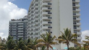 A tall, multi-story hotel with balconies on each floor, surrounded by palm trees. - Beautiful Studio on the Beach at The Decoplage (Miami Beach)