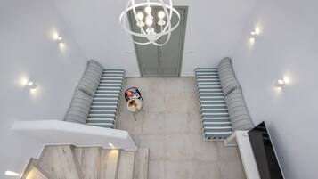 A staircase leading to a room with a chandelier, striped cushions, and a small table with items on it.