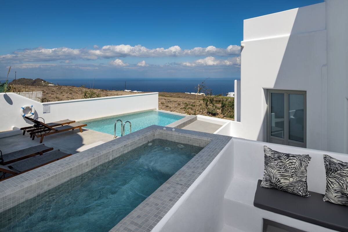 Un área de piscina moderna al aire libre con vista al mar, una silla de descanso y una pequeña terraza.