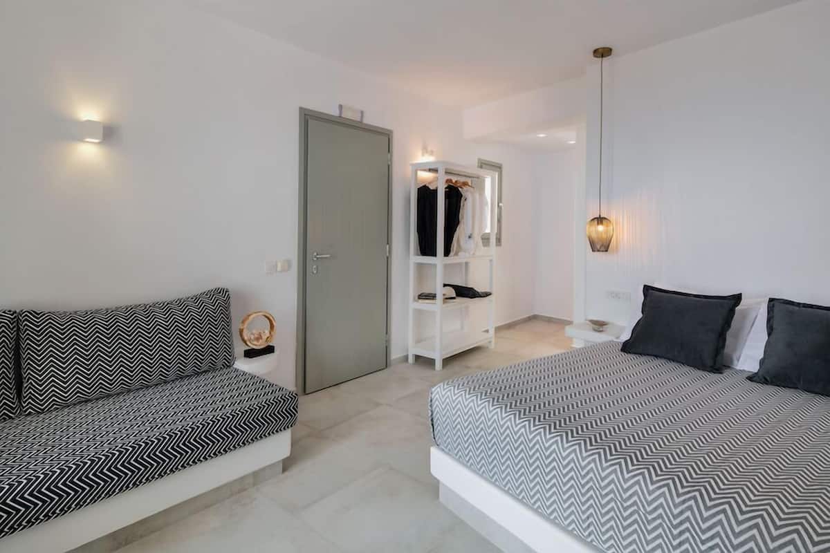 Un dormitorio moderno con cama, sofá, armario y espejo.