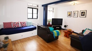 A living room with a sofa, a television, and a coffee table. - Great Location Shoreditch Spitalfields (London)