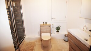 A modern bathroom with a toilet, sink, and shower. - Great Location Shoreditch Spitalfields (London)