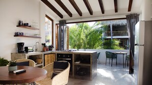 Eine moderne Küche mit Essbereich, ein Balkon mit Blick auf Palmen und eine kleine Sitzgelegenheit im Freien.