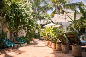 A patio with potted plants, a wooden table, and two blue chairs. - PAL.MAR Hotel Tropical (San Francisco)