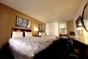 A hotel room with two beds, a desk, a chair, a TV, and artwork on the walls.