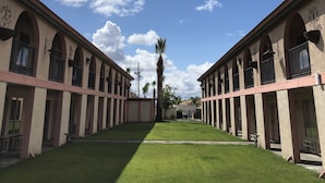 A courtyard with a central pathway flanked by two-story buildings with arched windows and balconies.