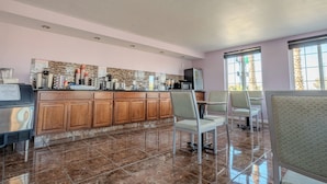 A spacious kitchen with wooden cabinets, a marble floor, and a large island with various appliances.