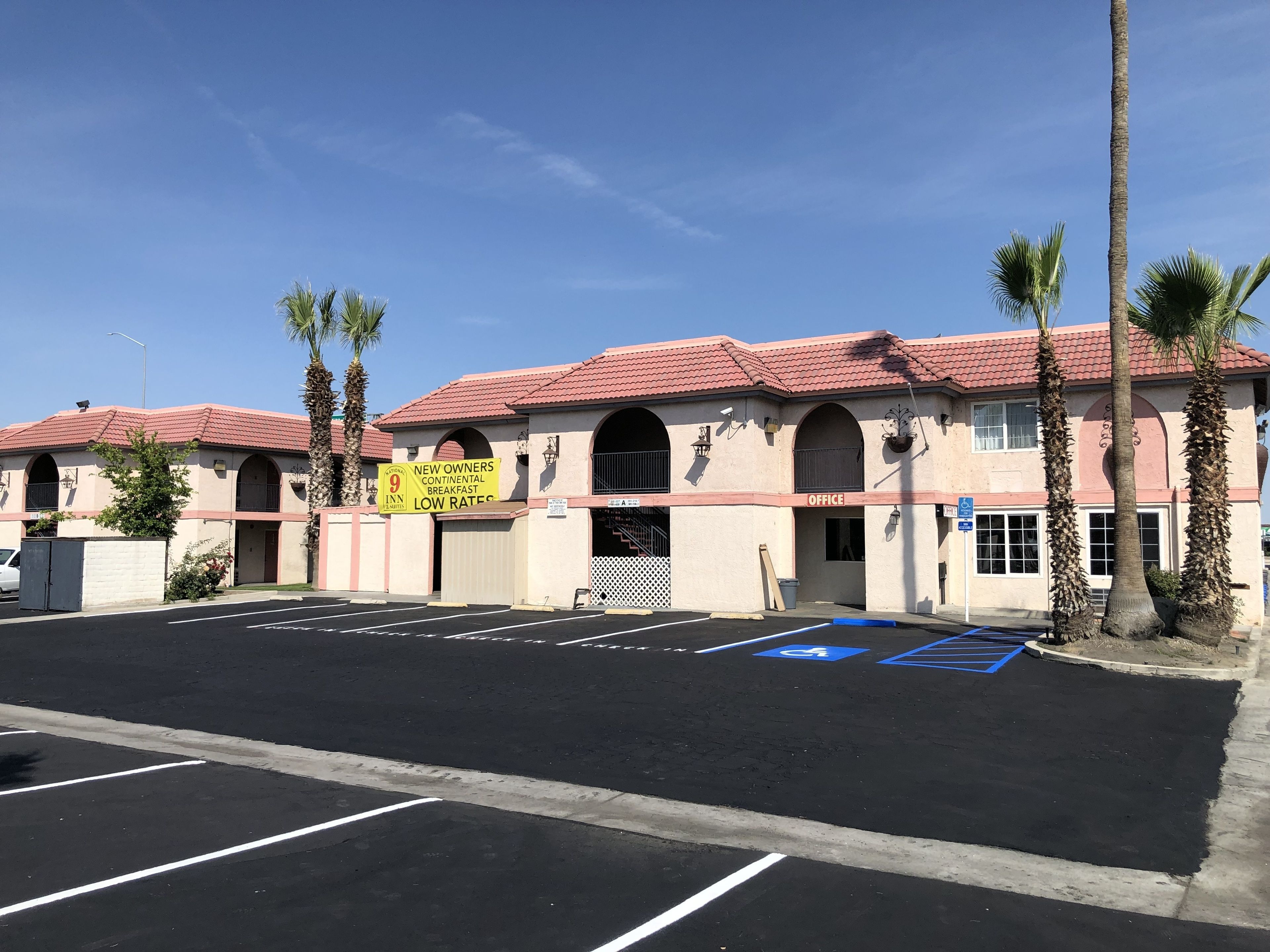 A building with a red-tiled roof, a sign for a continental breakfast, and a handicapped parking space.