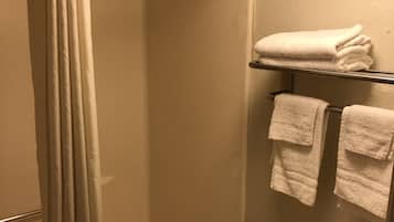 Un baño con cortina de ducha, bañera, inodoro y un perchero con toallas dobladas.