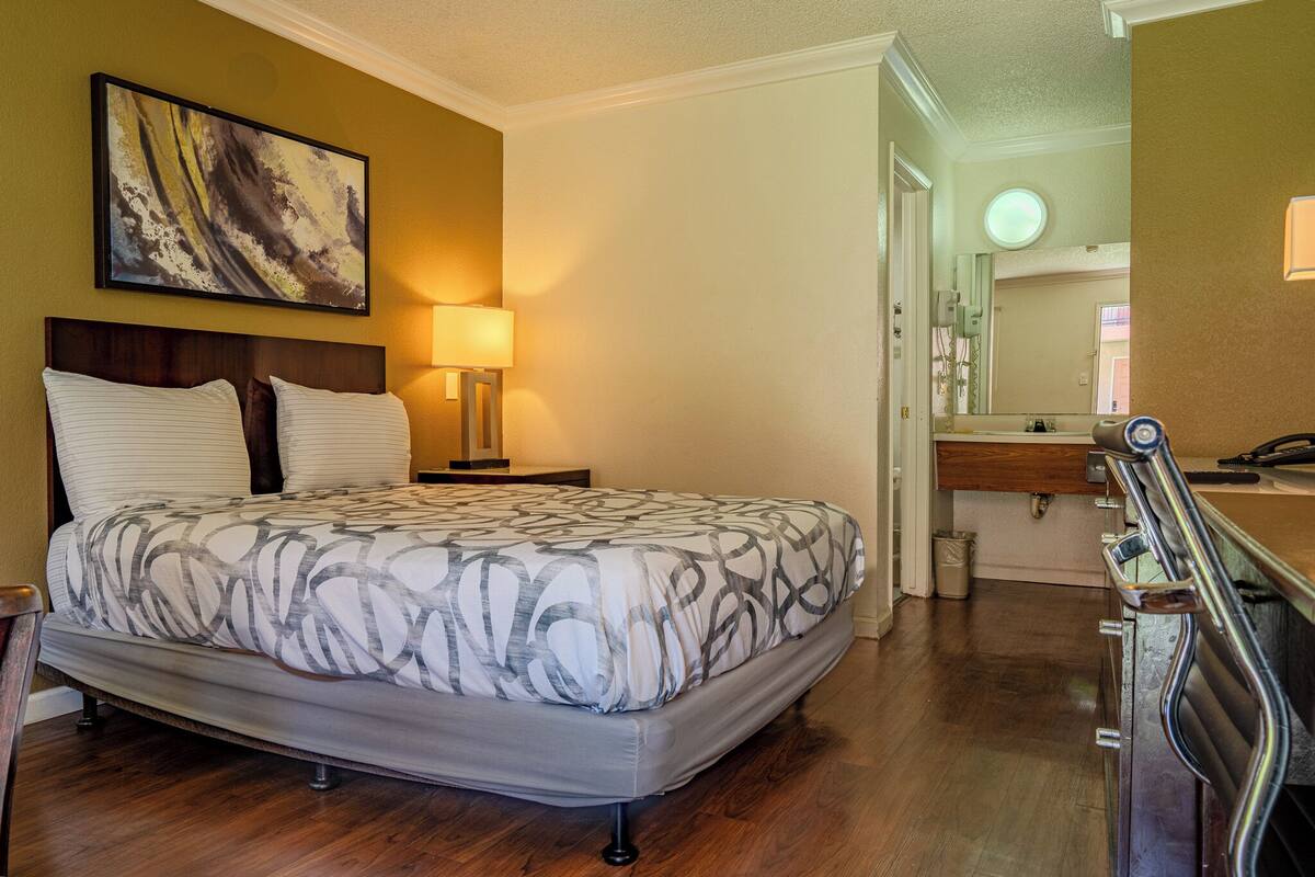 A bedroom with a bed, bedside lamp, and a painting on the wall.