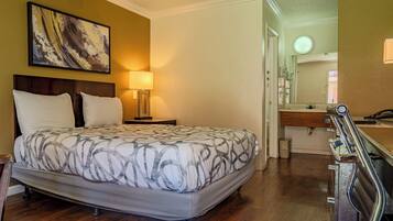 Un dormitorio con cama, lámpara de noche y un cuadro en la pared.