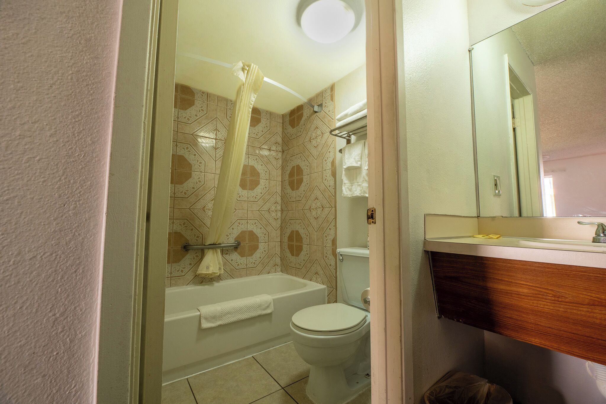 A bathroom with a bathtub, toilet, and a vanity with a mirror.