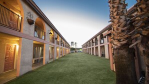 A courtyard with a central lawn, surrounded by buildings with arched windows and balconies.