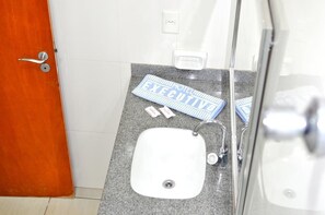 A bathroom with a white sink, a mirror, and a towel rack.