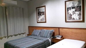 A hotel room with a bed, a bedside table, a nightstand, and two framed floral artworks on the wall. - Hotel Executivo (Araguaina)