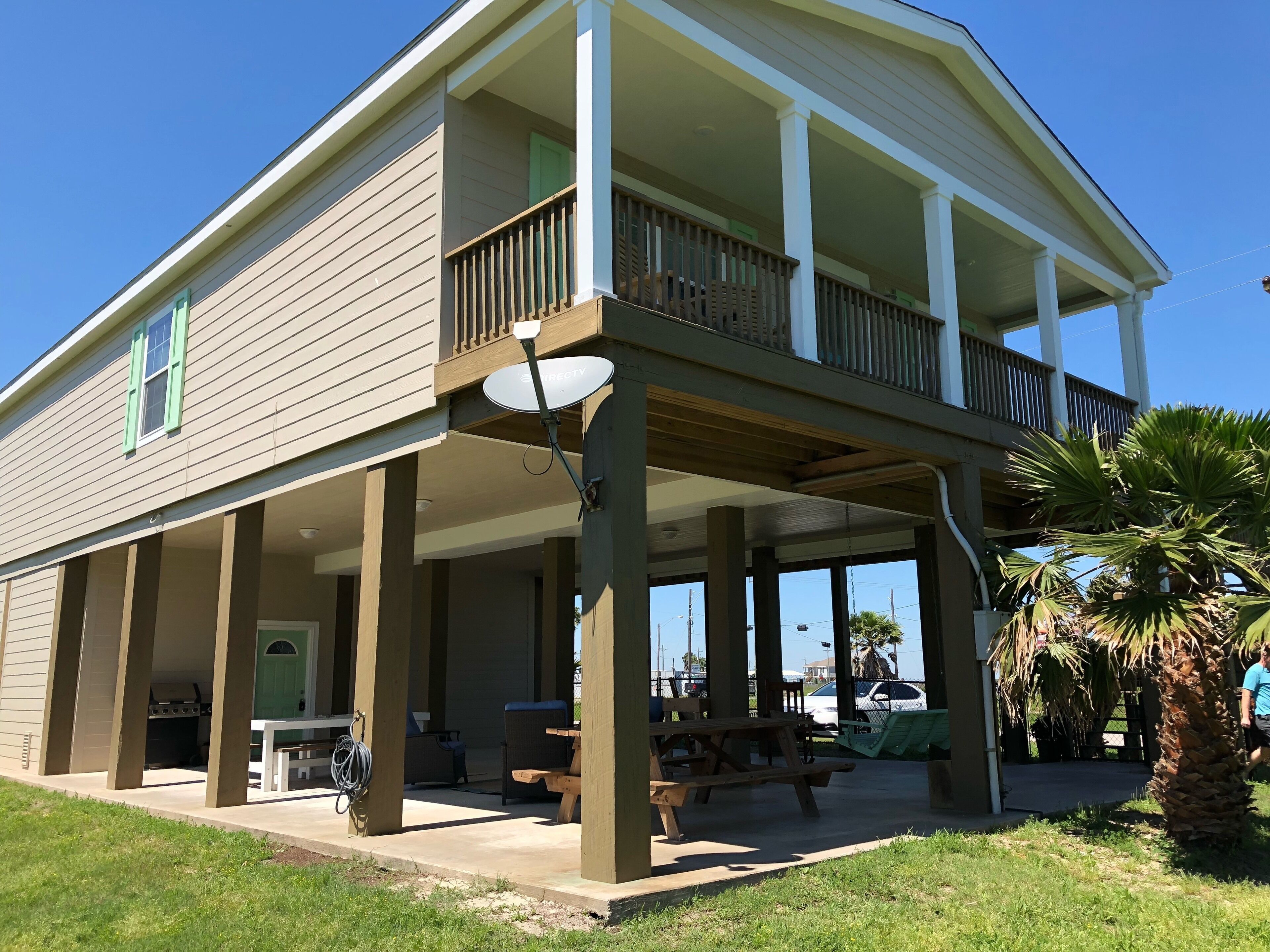 A two-story building with a balcony, outdoor seating area, and a satellite dish.