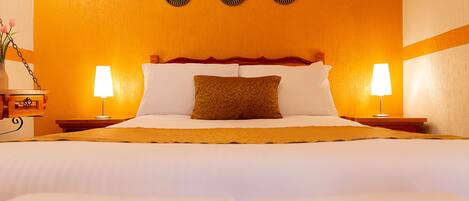 A hotel room with a large bed, two bedside tables with lamps, a decorative mirror, and a wall with three circular mirrors.