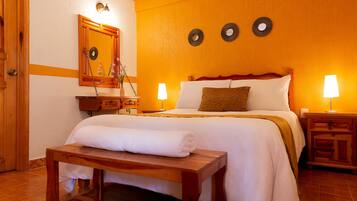 Habitación de hotel con cama, mesitas de noche, espejo y decoración en la pared.