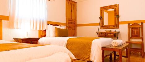 Una habitación de hotel con dos camas, un aparador de madera, un espejo y una ventana con cortinas.