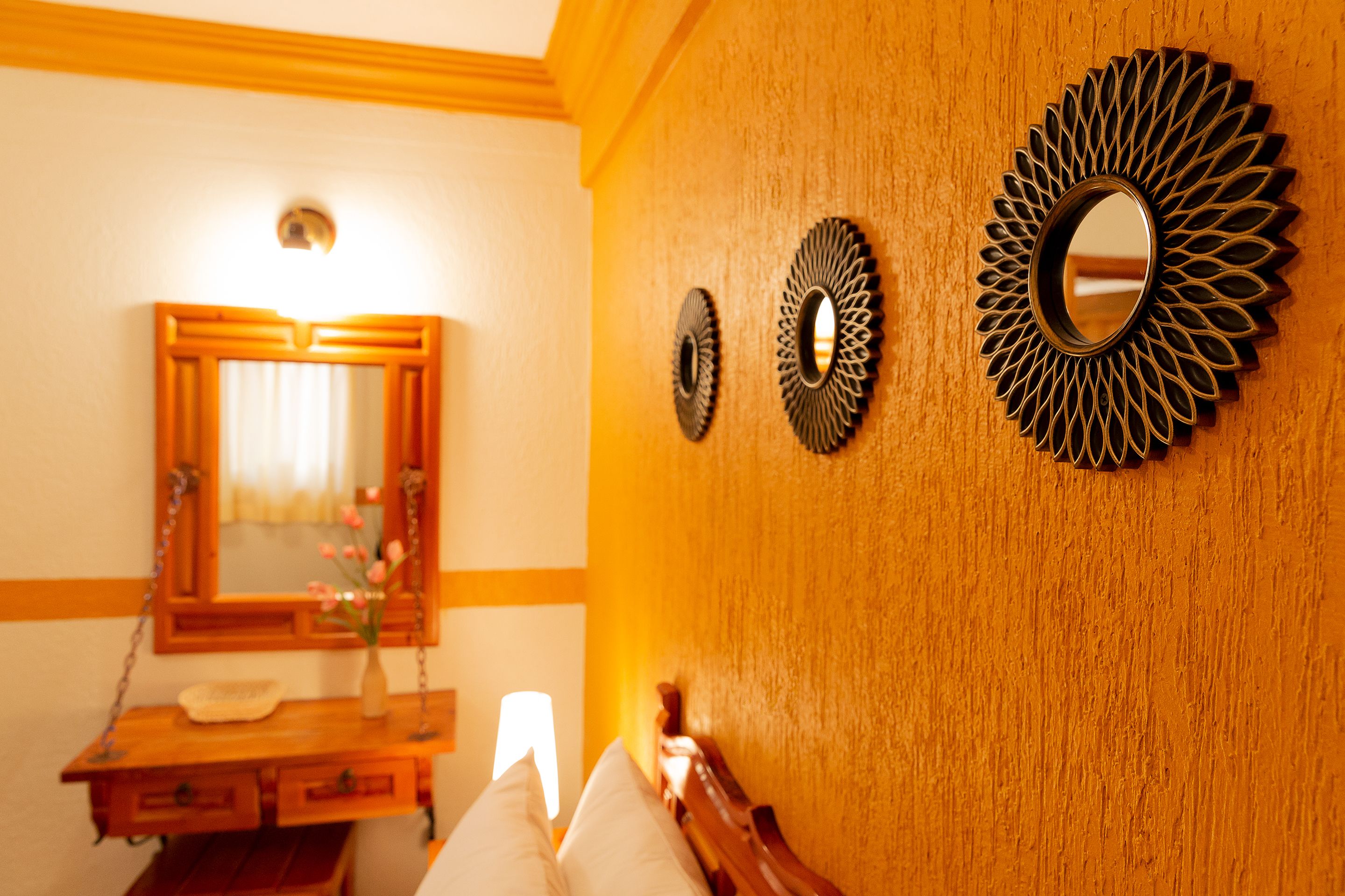 A bathroom with a wooden vanity, a mirror, and decorative wall sconces.
