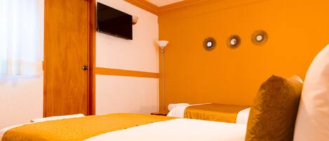 Habitación de hotel con cama, televisión y lámpara de pared.
