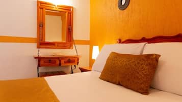 Een hotelkamer met een bed, nachtkastje, spiegel en een wandlamp.