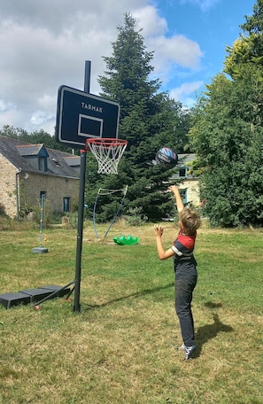 Niño jugando al baloncesto en un patio trasero con un aro que dice "TARMAK".