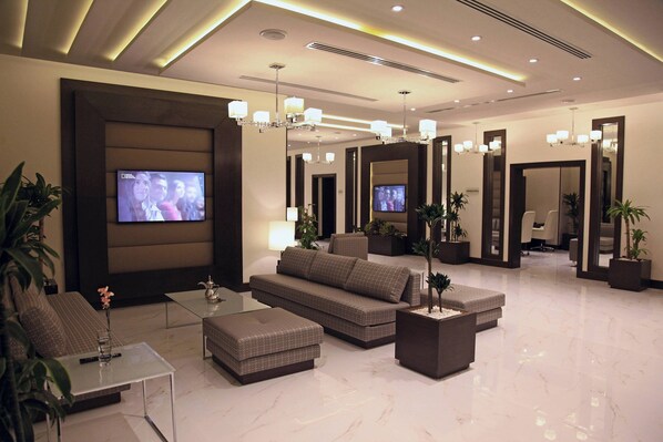 A modern lobby with a sofa, ottoman, and a flat-screen TV. - Marriott Executive Apartments Madinah (Madinah)