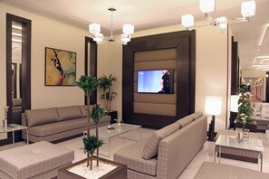 A modern hotel lobby with a sofa, coffee table, and a TV mounted on the wall. - Marriott Executive Apartments Madinah (Madinah)