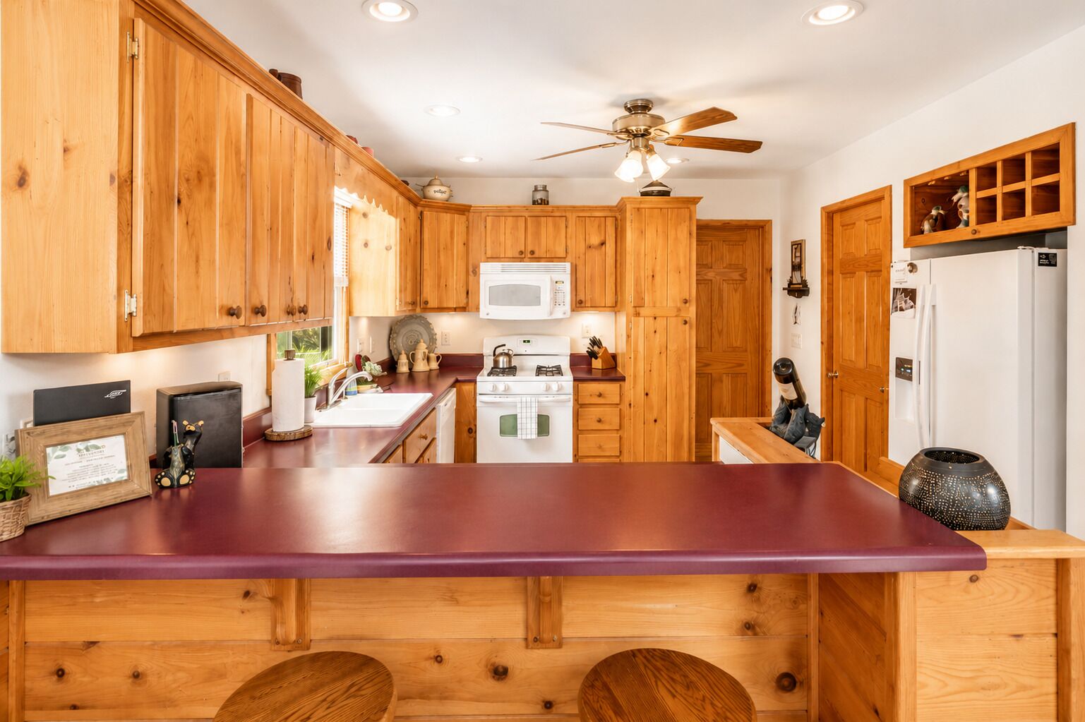 A kitchen with wooden cabinets, a microwave, a stove, and a ceiling fan.