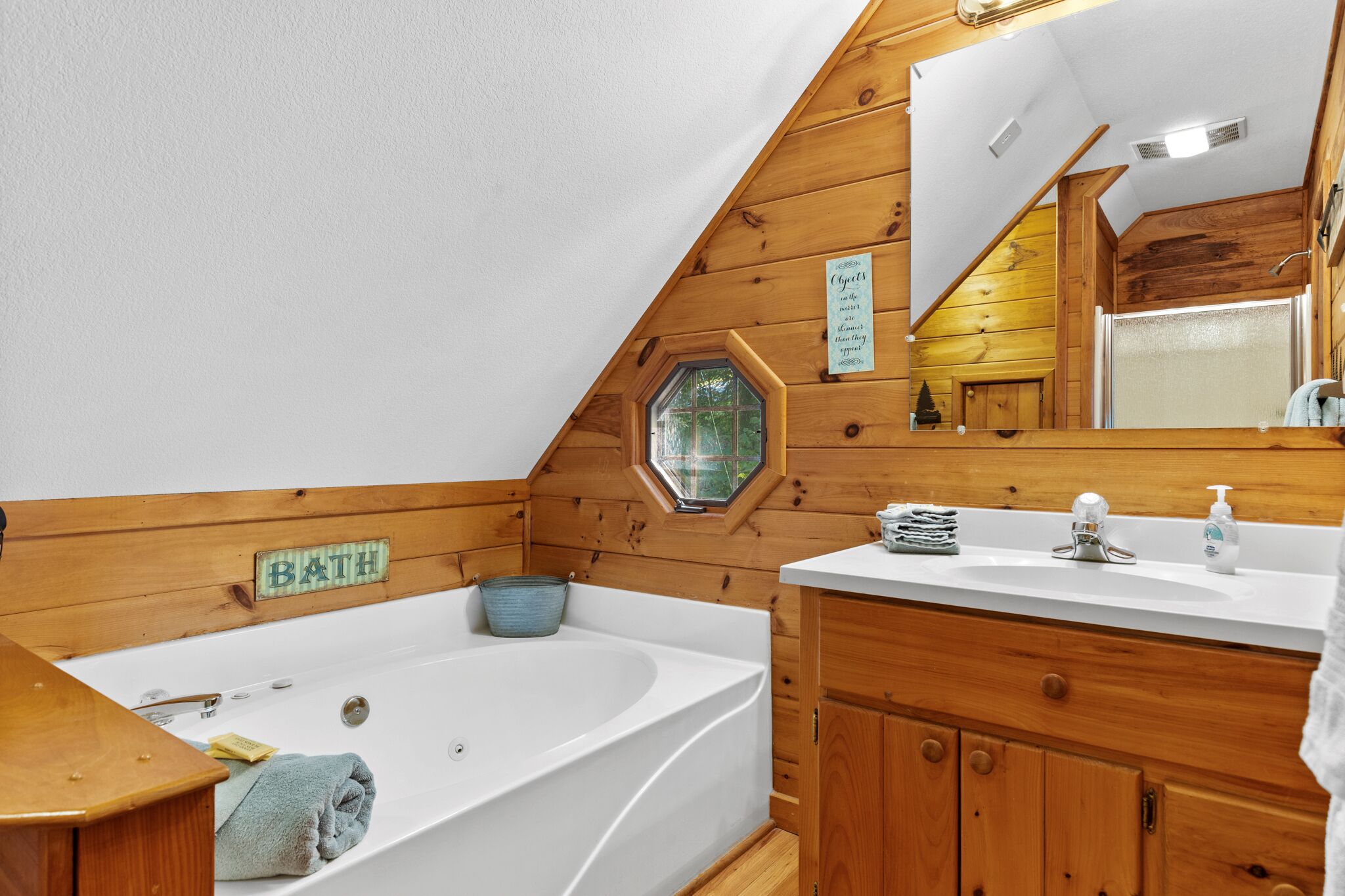 A wooden cabin bathroom with a bathtub, a sink, and a mirror.