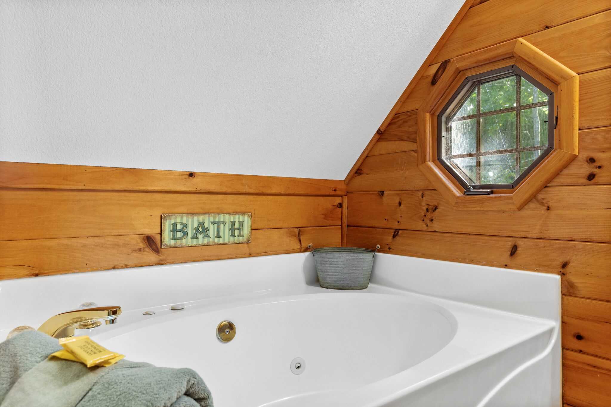 Una cabaña de madera con una bañera, un ventanal y un letrero que dice 'BATH'.